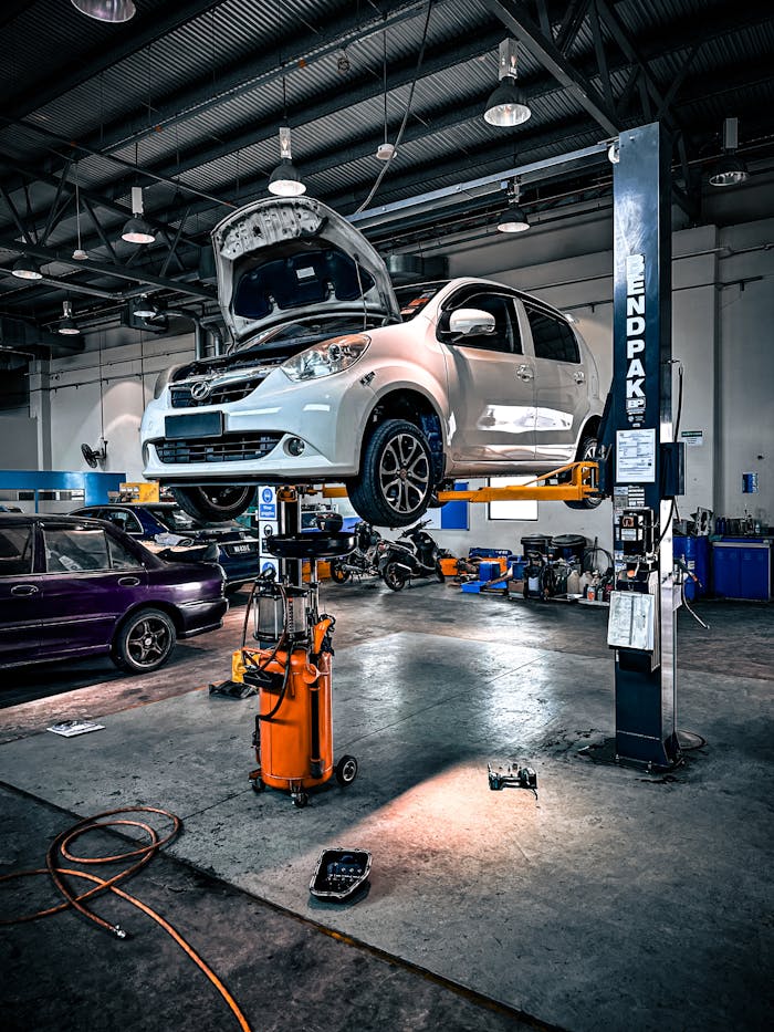 A car is lifted on a hydraulic lift in a well-equipped auto repair shop.